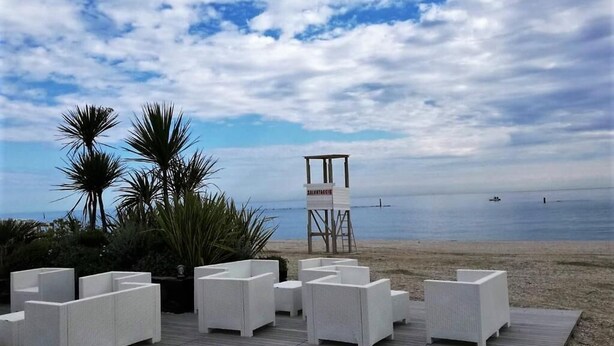 A beachside patio with white wicker furniture and a lifeguard tower in the background. - Family Hotel Sole (Vico del Gargano)
