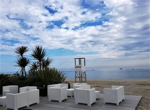 A beachside patio with white wicker furniture and a lifeguard tower in the background. - Family Hotel Sole (Vico del Gargano)