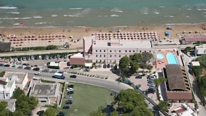 A coastal hotel with a swimming pool, beach umbrellas, and a parking lot. - Family Hotel Sole (Vico del Gargano)