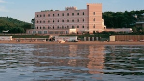 A large, historic building with multiple arches and a prominent tower, situated by a body of water. - Family Hotel Sole (Vico del Gargano)