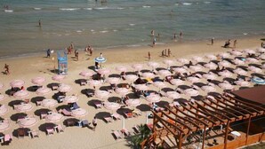 A beach with numerous umbrellas and sun loungers, a lifeguard tower, and a wooden structure. - Family Hotel Sole (Vico del Gargano)
