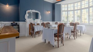 A dining area with tables set for six, white walls, and a large window with a view. - The Montana (Torquay)