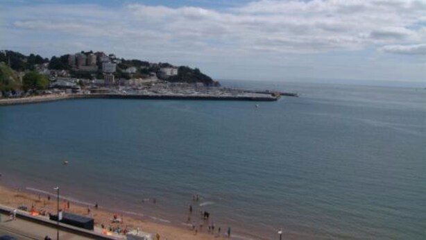 A coastal town with a beach, buildings along the shore, and a clear sky. - The Montana (Torquay)