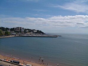 A coastal town with a beach, buildings along the shore, and a clear sky. - The Montana (Torquay)