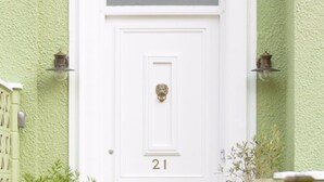 A white door with a sign above it reading "THE MONTANA" and the number "21" below. - The Montana (Torquay)