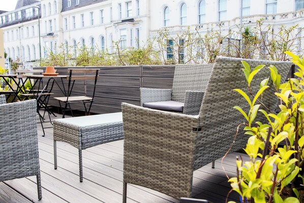 A rooftop patio with wicker furniture, a table, and chairs. - The Montana (Torquay)