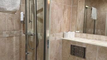 A bathroom with a glass-enclosed shower, a white sink, and a toilet.