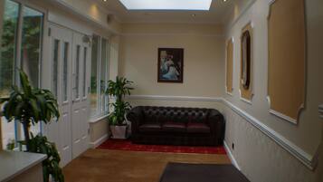 A room with a skylight, a large window, a sofa, a potted plant, and a painting on the wall.