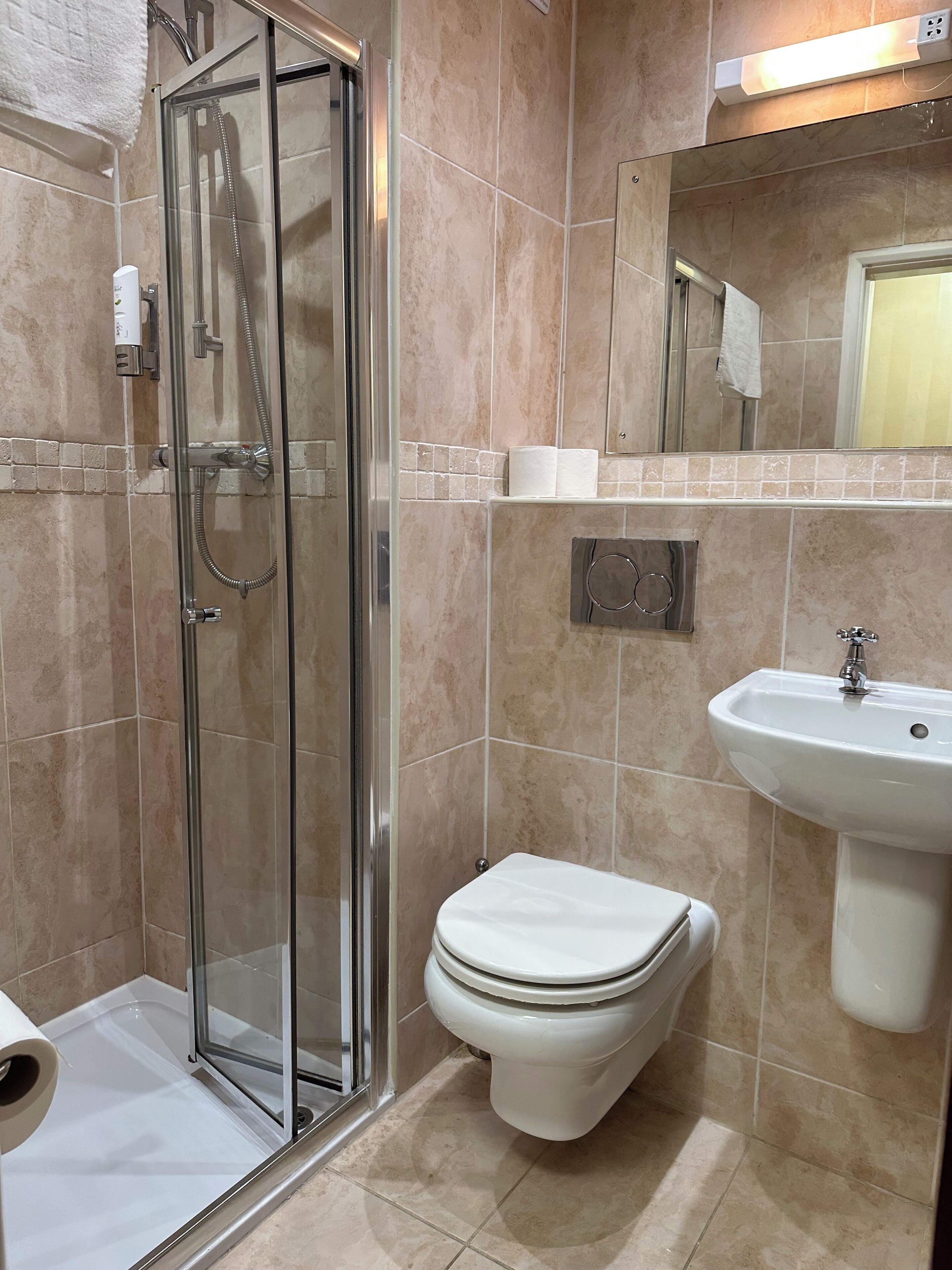 A bathroom with a glass-enclosed shower, a toilet, and a sink.