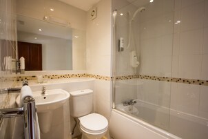 Un baño con lavamanos, inodoro y ducha con cerramiento de vidrio.