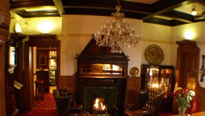 A cozy room with a fireplace, leather armchairs, a wooden coffee table, and a chandelier. - The Normanhurst Hotel (Sale)