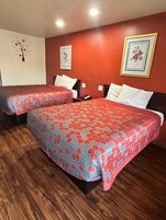 Habitación de hotel con dos camas, suelo de madera y paredes rojas.