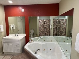 Un baño con lavamanos, tocador y una bañera grande.