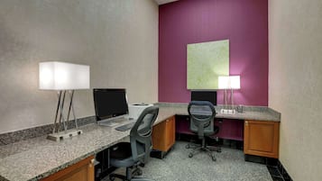 A hotel room with two desks, each with a computer and a lamp, and a large map on the wall.