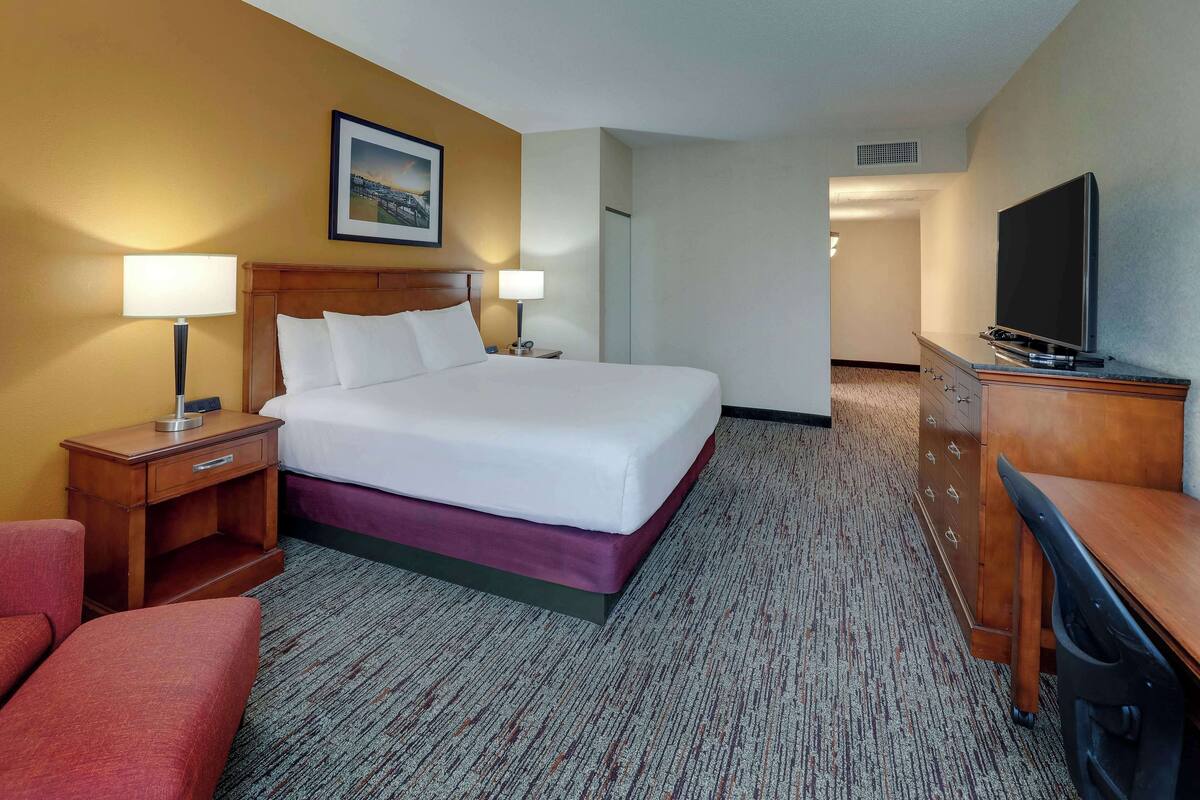Een hotelkamer met een bed, twee bedlampen, een televisie, een bureau en een stoel.