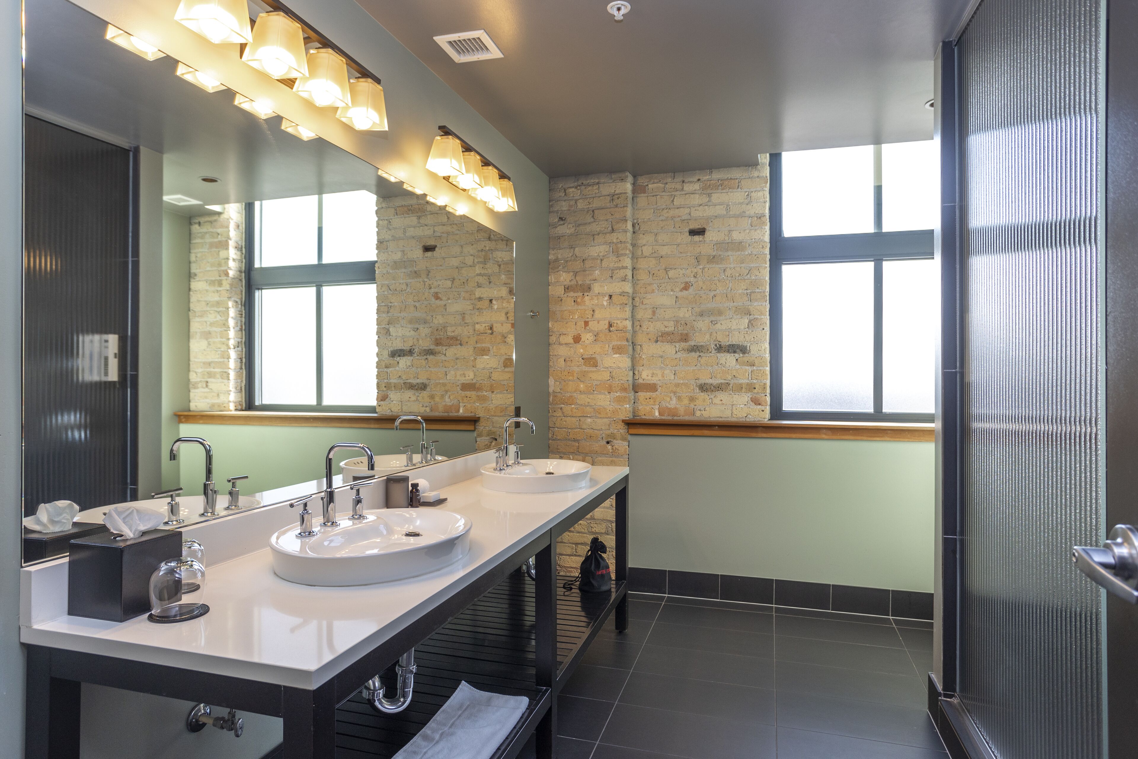 Un baño moderno con dos lavamanos, un espejo grande y una zona de ducha.