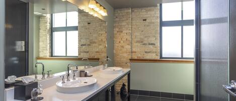 Un baño moderno con dos lavamanos, un espejo grande y una zona de ducha.