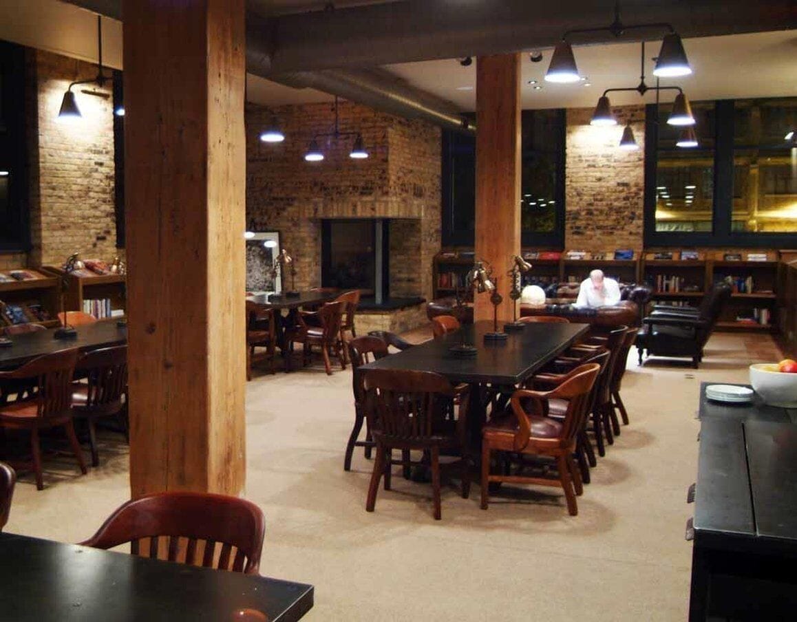 Un'ampia sala da pranzo con pareti in mattoni, tavoli e sedie in legno e lampade a sospensione.