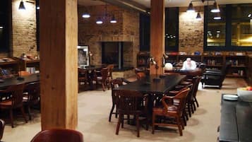 Un'ampia sala da pranzo con pareti in mattoni, tavoli e sedie in legno e lampade a sospensione.