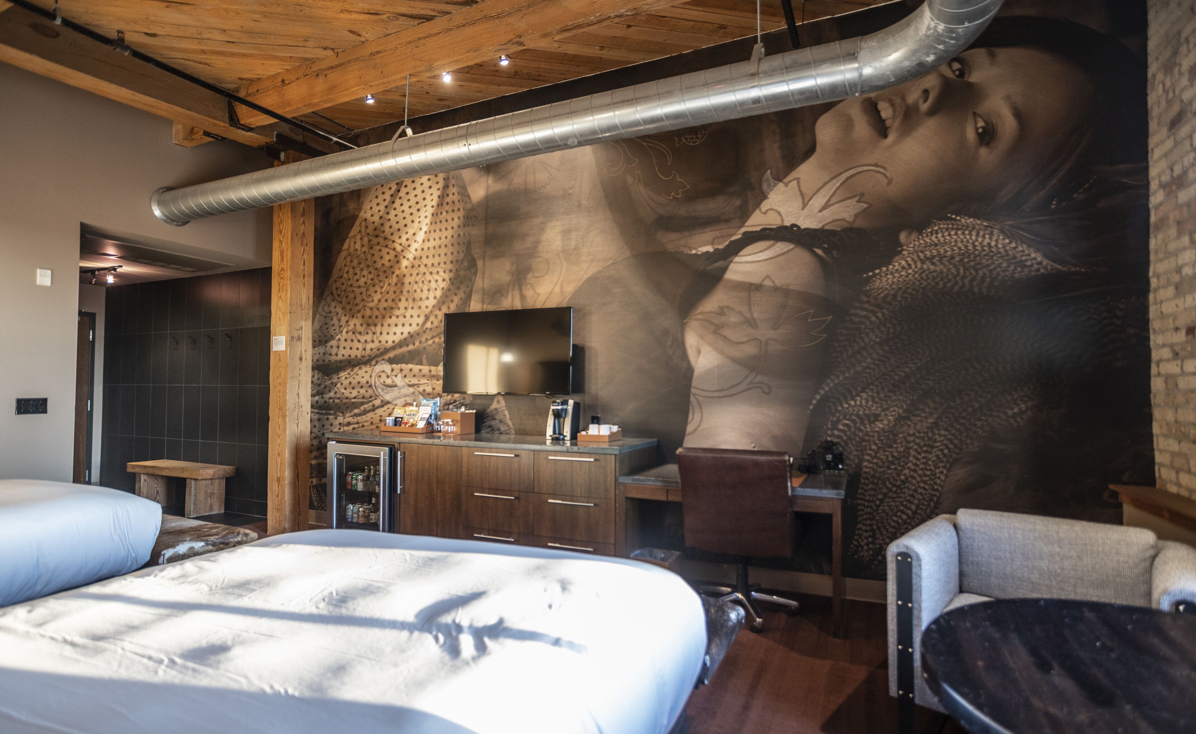 Un dormitorio moderno con un mural grande, una cama, un escritorio y una silla.