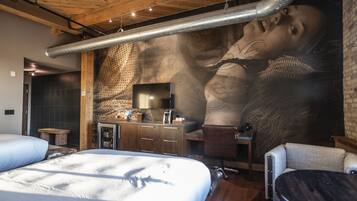 A modern bedroom with a large mural, a bed, a desk, and a chair.
