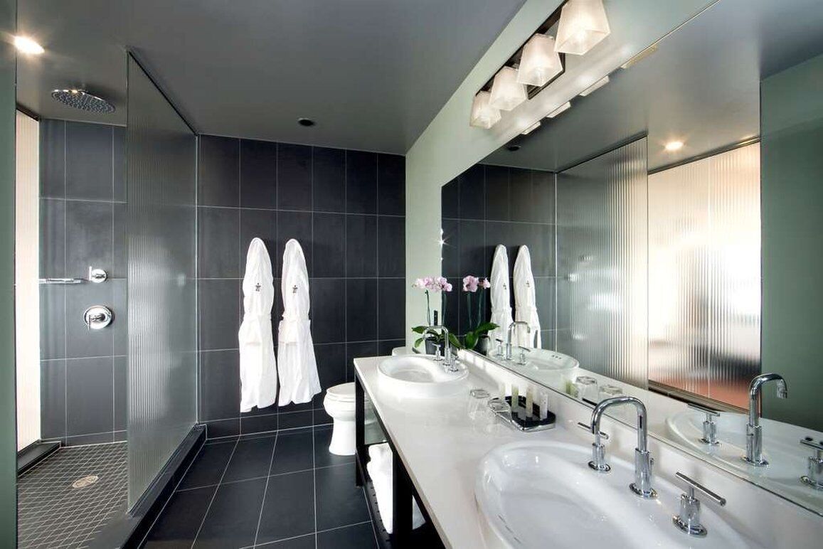 A modern bathroom with two sinks, a large mirror, and a shower area.