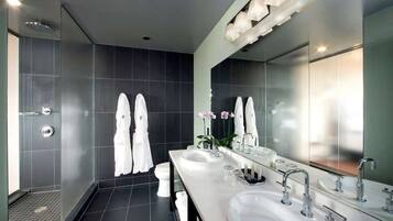 A modern bathroom with two sinks, a large mirror, and a shower area.
