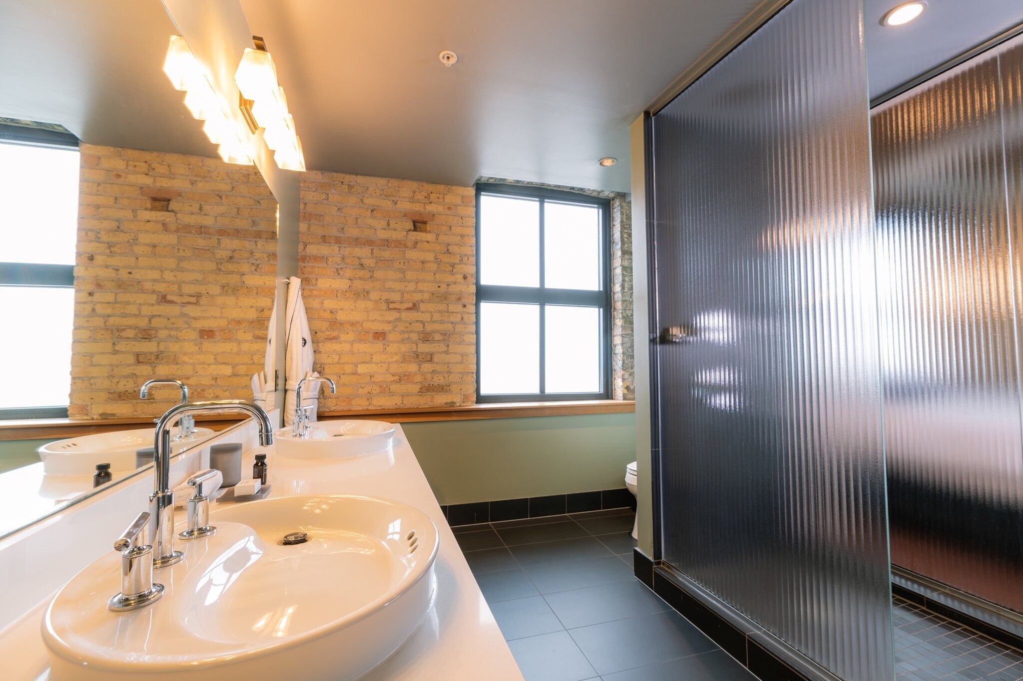 A modern bathroom with a large mirror, two sinks, and a shower enclosure.
