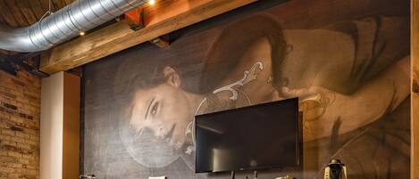 A bar area with a large mural, a flat-screen TV, and a coffee machine.