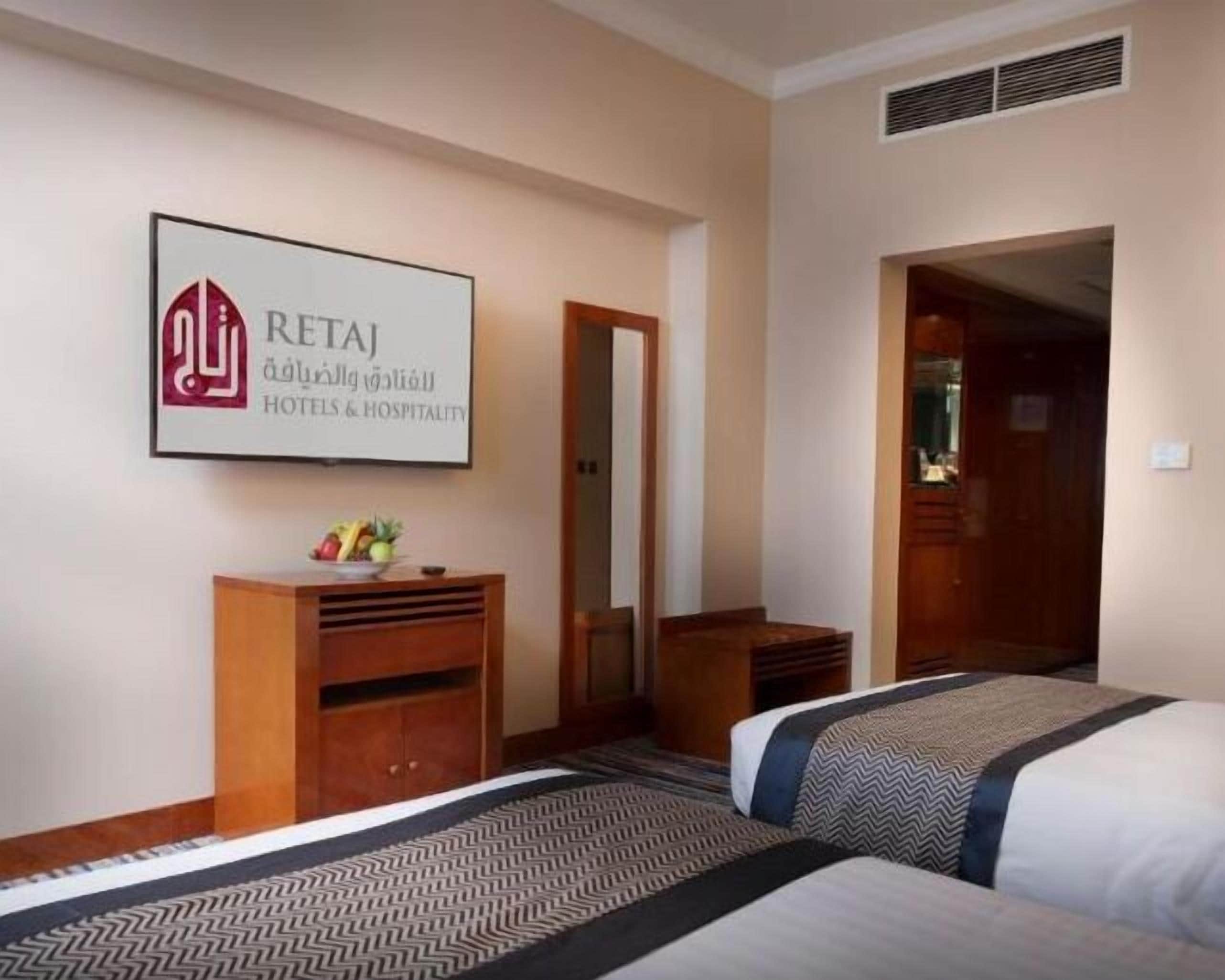 Habitación de hotel con dos camas, un aparador de madera, un espejo y un cartel enmarcado en la pared.