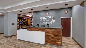 A hotel reception area with a modern design, featuring a reception desk, a welcome sign, and a minibar. - Hampton Inn & Suites Dallas-DeSoto (DeSoto)