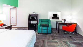 Une chambre d’hôtel équipée d’un lit, d’un bureau avec une chaise, d’une télévision et d’un four à micro-ondes.