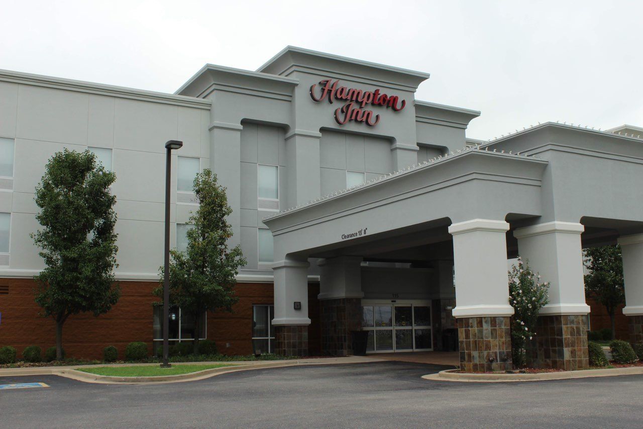 A Hampton Inn hotel with a modern facade, a covered entrance, and a parking lot.