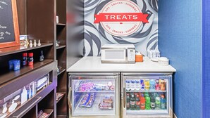 A beverage refrigerator with a 'TREATS' sign above it, containing various drinks and snacks.