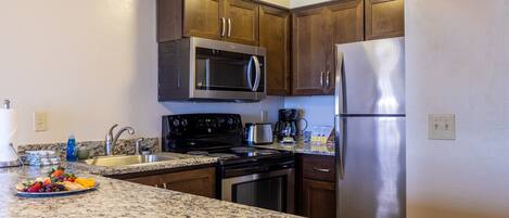 Cocina con encimeras de granito, electrodomésticos de acero inoxidable y armarios de madera.