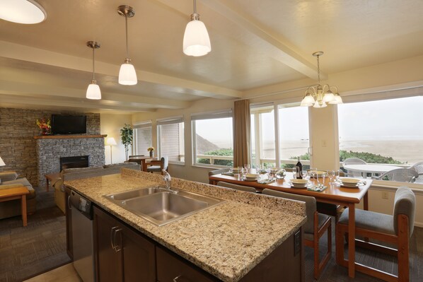 A kitchen with granite countertops, stainless steel sink, and a dining area with a table set for four. - Driftwood Shores Resort And Conference Center (Florence)