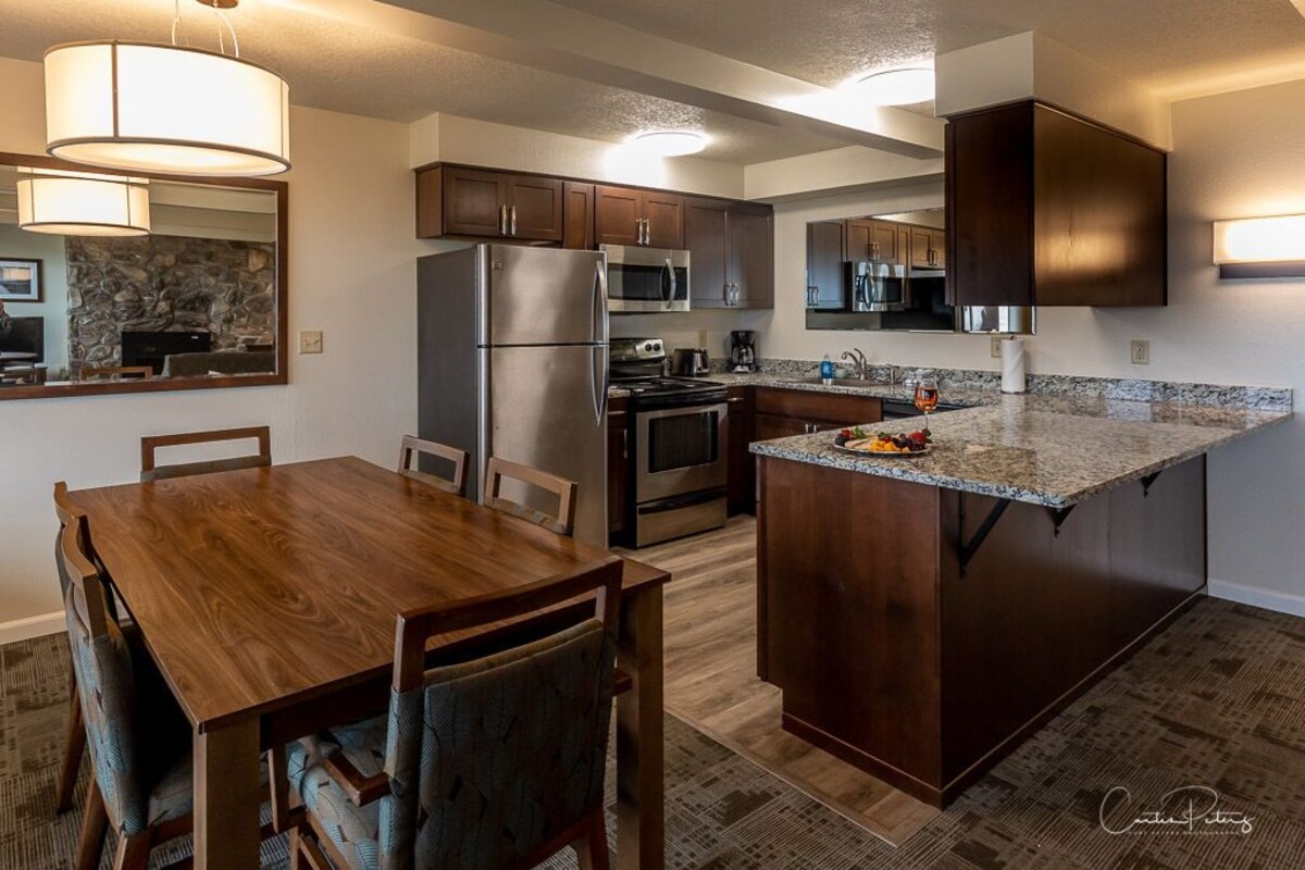 A modern kitchen with dark wood cabinets, stainless steel appliances, and a granite countertop.