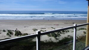 A beach view from a balcony with a railing, ocean waves, and people in the distance. - Driftwood Shores Resort And Conference Center (Florence)
