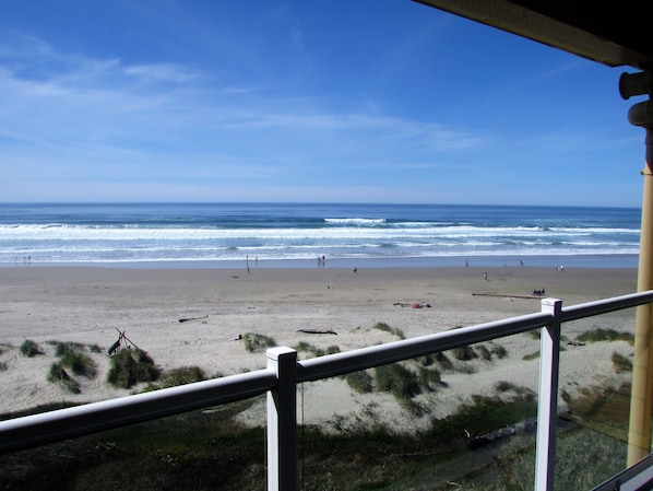 A beach view from a balcony with a railing, ocean waves, and people in the distance. - Driftwood Shores Resort And Conference Center (Florence)