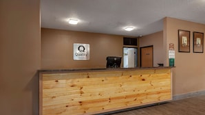 A reception desk with a wooden panel design, a sign indicating 'Quality by Choice Hotels', and a Dell computer on the counter. - Quality Inn Redgranite (Redgranite)