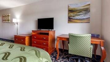 A hotel room with a bed, a desk with a chair, a dresser, a flat-screen TV, and a painting on the wall.