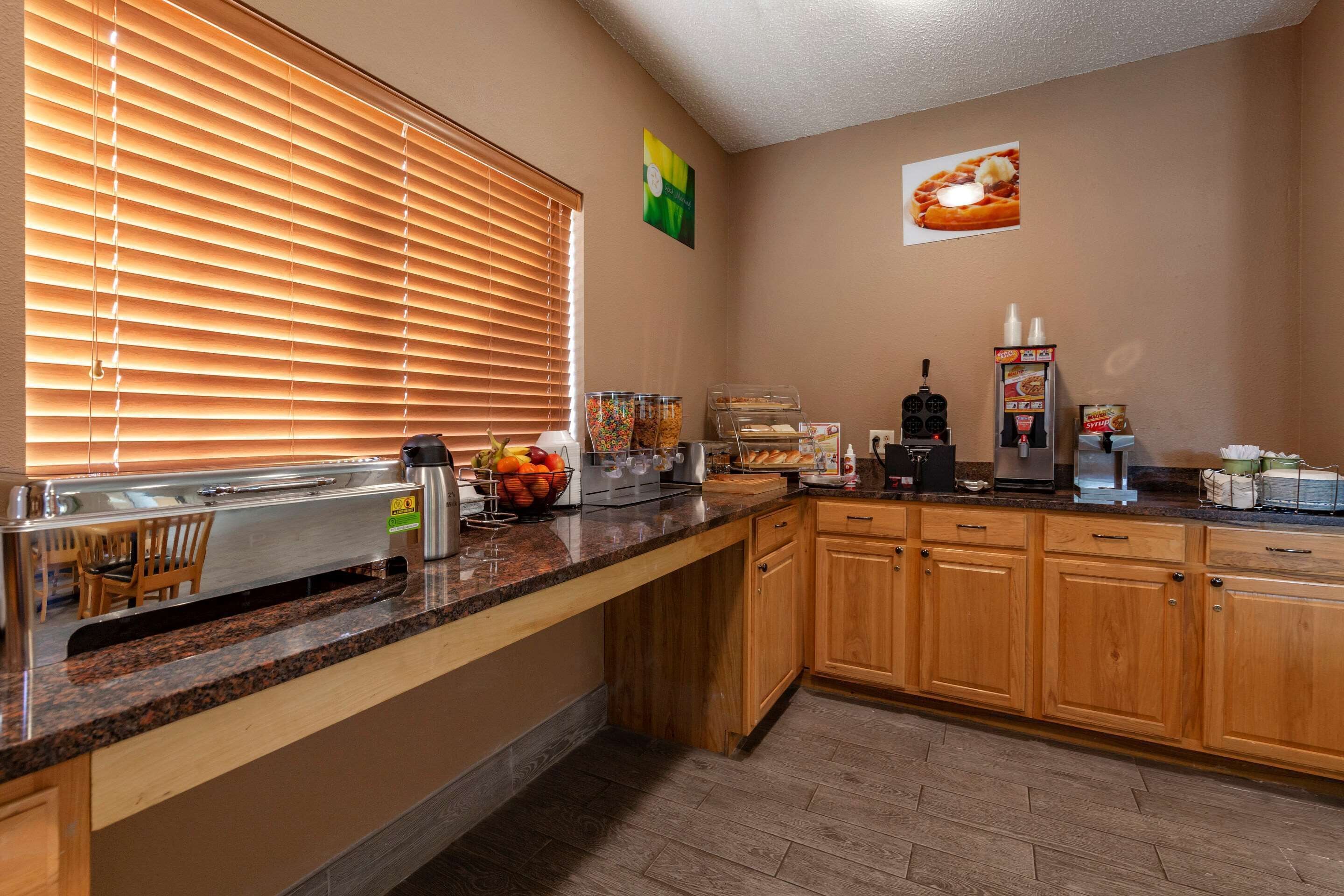 Una cocina con encimera de granito, armarios de madera, cafetera y frutero.