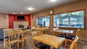 A restaurant with wooden tables and chairs, a brick fireplace, and large windows. - Quality Inn Redgranite (Redgranite)
