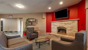 A modern living room with a fireplace, comfortable seating, and a flat-screen TV. - Quality Inn Redgranite (Redgranite)