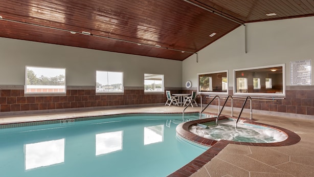 An indoor swimming pool with a hot tub, wooden ceiling, and windows with views. - Quality Inn Redgranite (Redgranite)