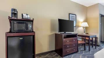 A compact hotel room with a kitchenette, a flat-screen TV, a desk with a chair, and a bed.