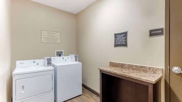 A laundry area with two Whirlpool washers, a sign indicating guest laundry use, and a storage sign.
