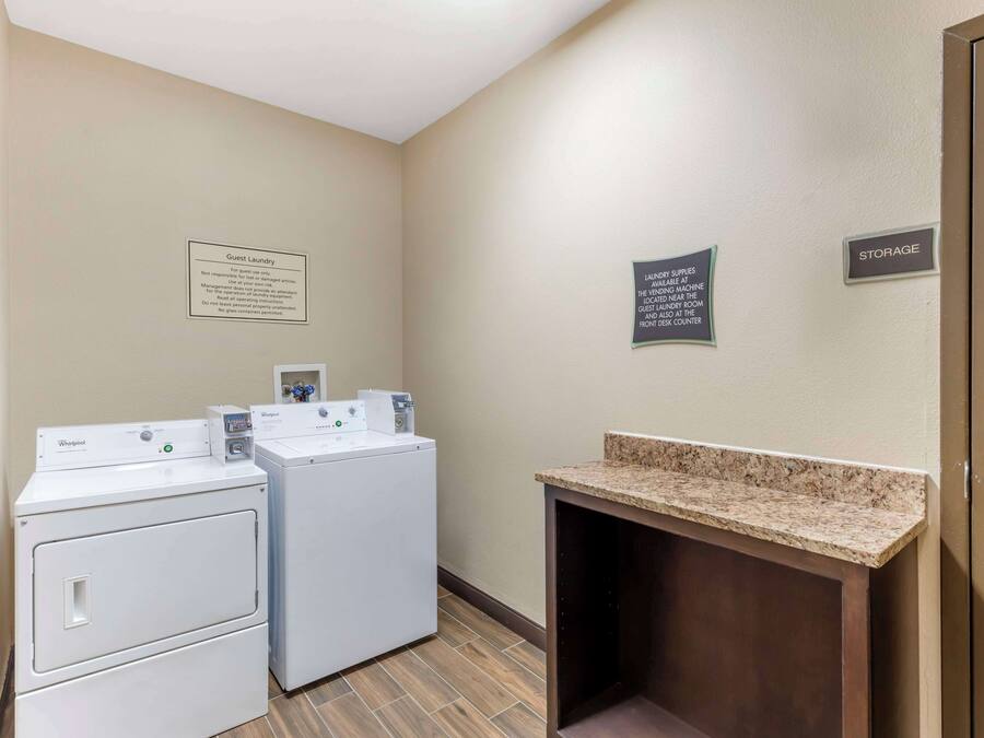 A laundry area with two Whirlpool washers, a sign indicating guest laundry use, and a storage sign.
