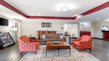 A spacious living room with a brown sofa, two patterned armchairs, and a wooden coffee table.