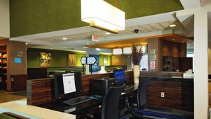 A hotel lobby with multiple computer workstations, a reception desk, and a green wall with artwork.